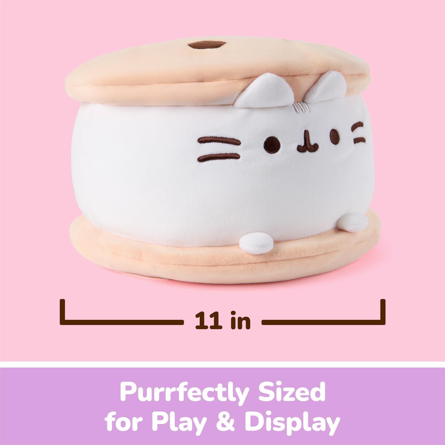 A plush cat-shaped storage box or container shown on a pink background with a dimension line indicating 11 inches wide. The product is white with beige top and bottom layers and simple embroidered facial features.