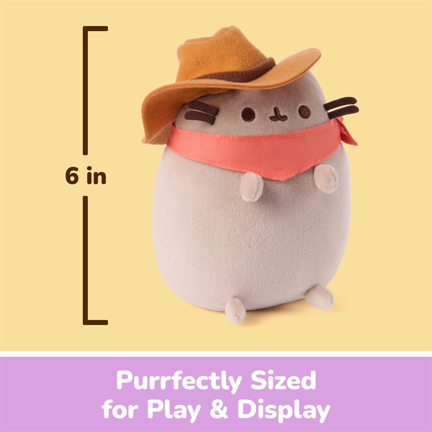 A Pusheen plush toy wearing an orange hat and pink bandana, shown on a pale yellow background with a height marker reading 6 in and a purple banner that says 'Purrfectly Sized for Play & Display'.